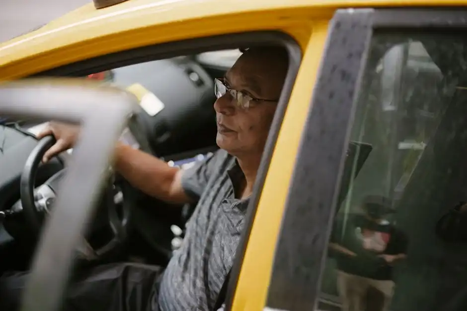 Middle aged driver at steering wheel of yellow automobile