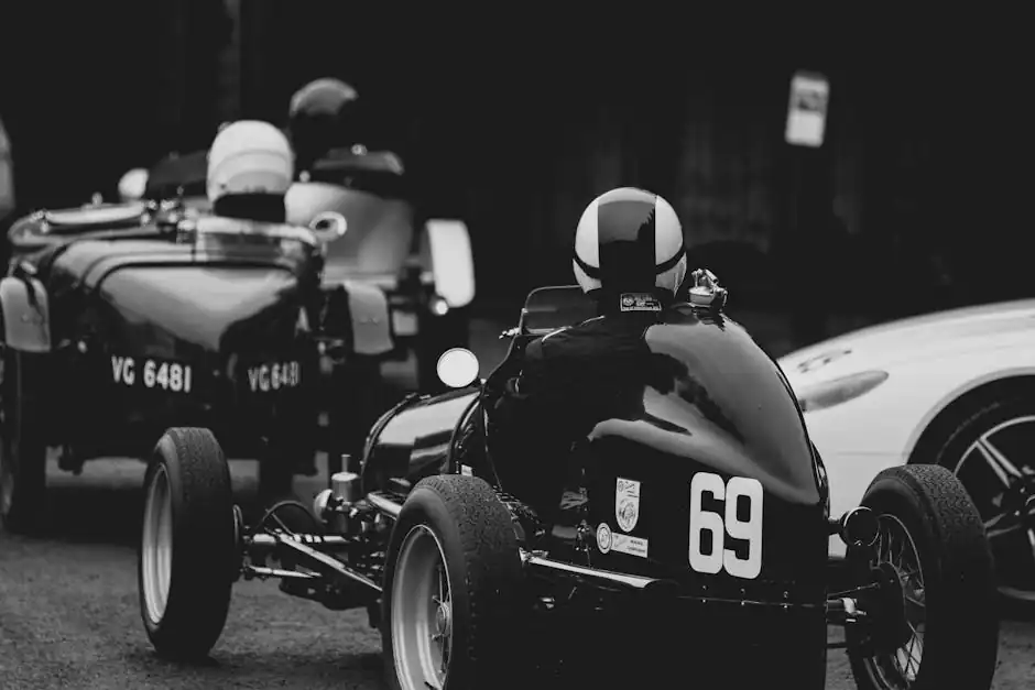 Black and white photo of a vintage car race with classic designs and helmets.