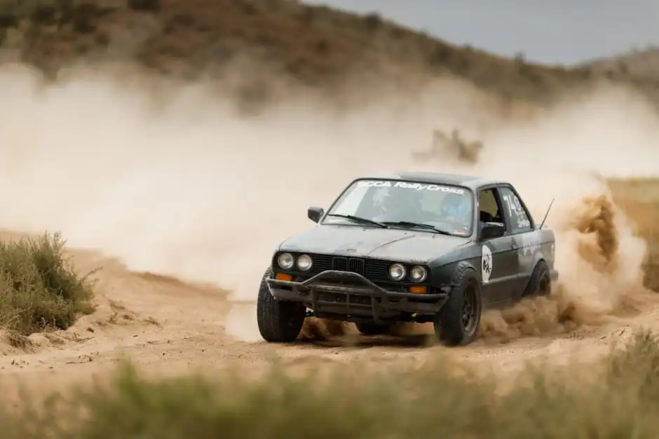 An off-road rally car speeds through the sandy terrain, creating a dramatic dust trail.