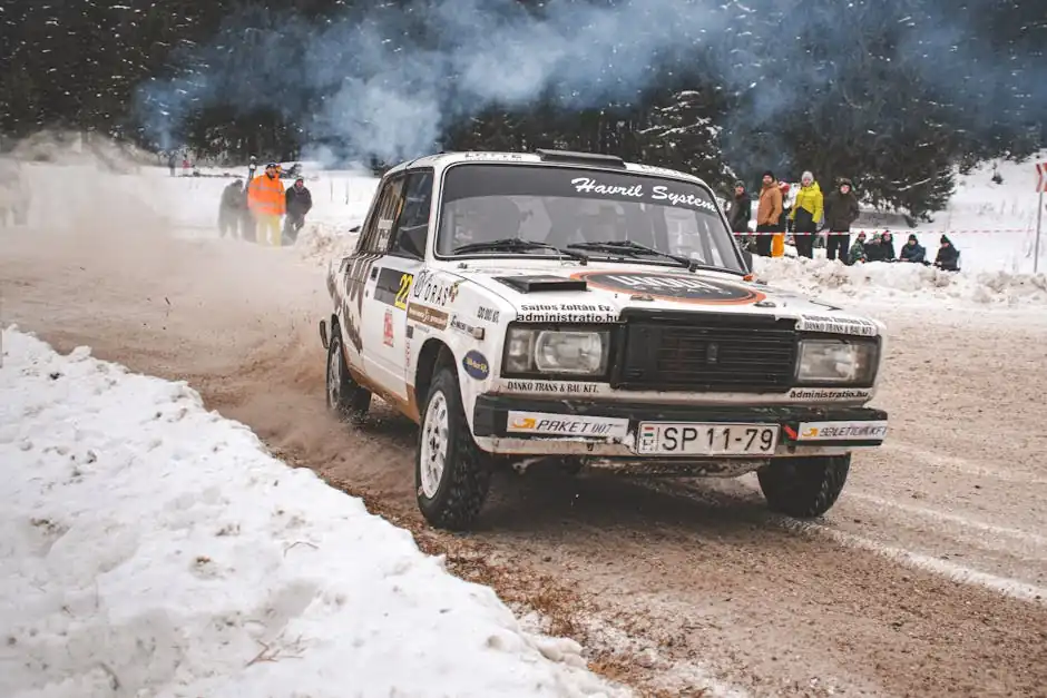 Dynamic rally car racing on snowy forest road in Comandău, Romania, showcasing speed and skill.