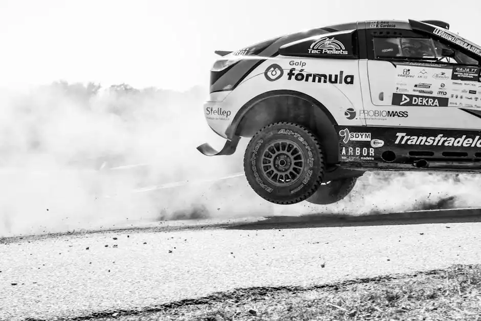 Dynamic black and white image of a rally car in motion, kicking up dust during a race.